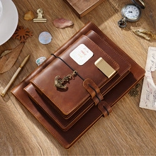 Close-up of vintage brown leather notebook set with metal anchor charm on wooden table
