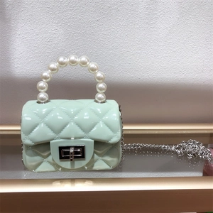 Close-up of mint green PVC jelly bag featuring quilted pattern and pearl handle detail