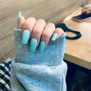 Primer plano de uñas postizas estilo ballerina azul claro mate sobre una manga gris