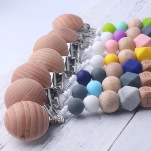 Silicone and beech wood baby pacifier clip chain with colorful beads on white wood surface