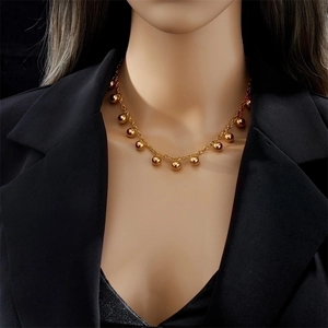 Minimalist gold bead titanium steel necklace worn by a model on a black background