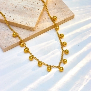 Minimalist gold titanium chain necklace with small round bead pendants on stone