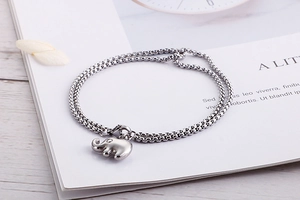 Detail of silver stainless steel link chain bracelet with a polished elephant charm