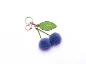 Detail of purple faux fur cherry keychain with green woven leaf and gold metal lobster clasp