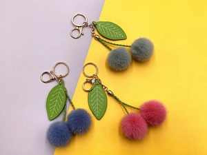 Macro view of plush cherry keychains in pink, purple and green with soft faux fur balls