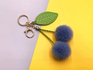 Close-up of purple faux fur cherry keychain with green leaf and golden lobster clasp