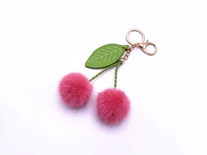 Close-up of cute pink plush cherry keychain with green leaf and golden metal hardware