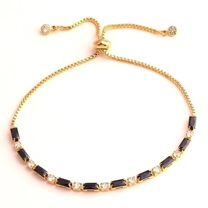 Detail of gold bracelet with black rectangle zircon and clear stones featuring slider clasp
