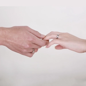 Close-up of a couple wearing minimalist silver beveled edge stainless steel rings