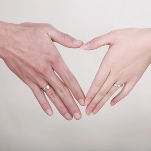 Close-up of couples hands forming a heart shape wearing silver stainless steel rings