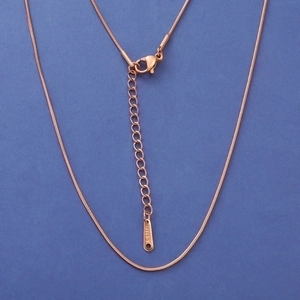 Detail of rose gold snake chain necklace with lobster clasp and S-STEEL tag on blue base