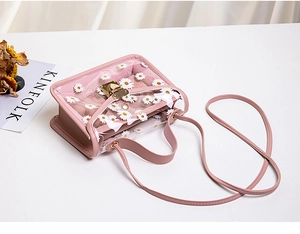 Detail of pink transparent PVC crossbody bag with white daisy print and slim strap