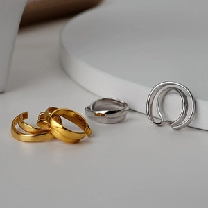 Close-up of minimalist layered sterling silver ear cuffs in gold and silver finishes