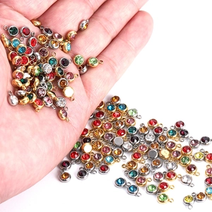 Close-up of colorful round birthstone pendants with metal base held in hand