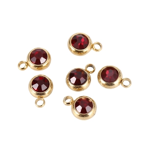 Detailed view of six gold-plated round charms with multi-faceted red crystals for DIY jewelry