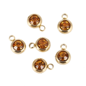 Macro view of six amber round crystal birthstone charms with gold plated bases for DIY jewelry