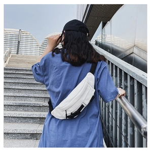 Weiße Canvas-Brusttasche am Rücken eines Models in minimalistischer Außenumgebung