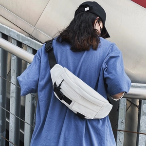 Outdoor-Aufnahme einer weißen Canvas-Brusttasche mit schwarzem Gurt und Schnallenverschluss
