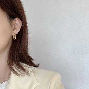 Close-up of a model wearing chunky gold S925 sterling silver C-shaped hoop earrings