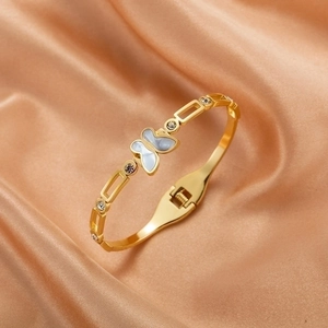 Elegant 18K gold butterfly bangle with shell inlay and cubic zirconia on silk background