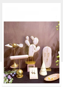 Detail of pink velvet jewelry display set with cactus stand and golden metal accents