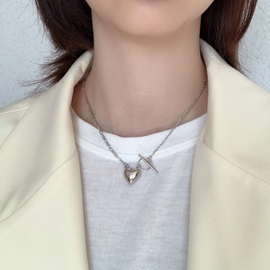Detailed view of silver heart pendant with Figaro chain and toggle clasp on a model