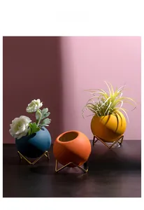 Detailed view of spherical ceramic mini vases in blue, orange and yellow with metal stands