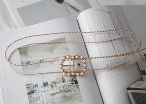 Detail of transparent belt with gold chain trim and pearl-encrusted metal buckle