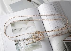 Detail of a thin transparent belt featuring a sparkling rhinestone sunflower buckle