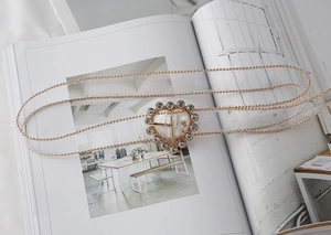 Macro view of gold metal bead belt with rhinestone-encrusted heart buckle on a magazine