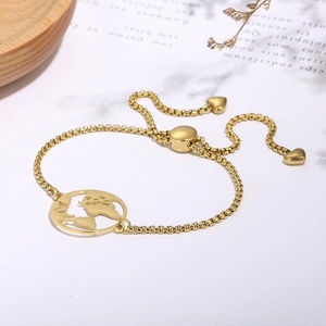 Detail of adjustable gold world map bracelet with heart charms on a decorative tray