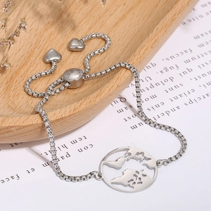 Detail of adjustable stainless steel world map bracelet with heart charms on wood tray