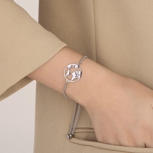 Close-up of adjustable stainless steel world map bracelet worn with a beige blazer