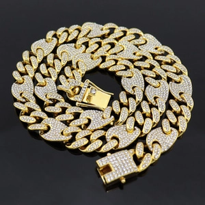 Macro detail of gold Cuban link chain necklace with sparkling crystals on black surface