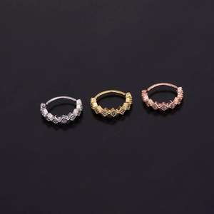 Close-up of three zirconia cartilage earrings in silver, gold, and rose gold finishes