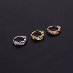 Macro shot of twisted cartilage hoop earrings in silver, gold, and rose gold with zircon