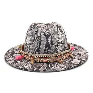 Détail d'un chapeau fedora bohème avec motif serpent, glands colorés et coquillages