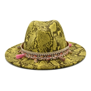 Détail d'un chapeau fedora jaune motif serpent avec ruban ethnique et pompons colorés