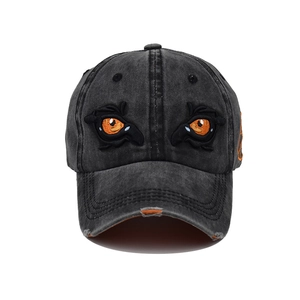 Detailed view of orange eyes embroidery on washed black cotton baseball cap