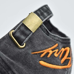 Detail view of washed dark grey denim baseball cap with adjustable bronze metal buckle