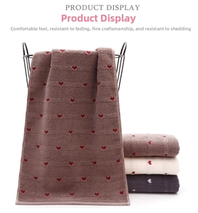 Detailed view of soft heart-patterned cotton towels in brown, white, and grey colors