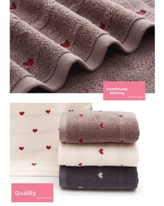 Detailed close-up of heart-patterned jacquard cotton towels in grey, beige, and purple