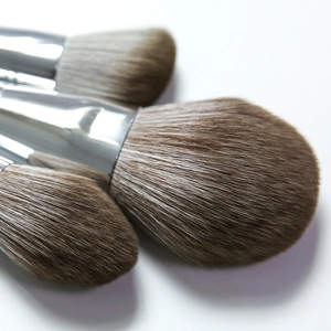 Set of 3 makeup brushes with silver ferrules and soft brown gradient bristles on white background