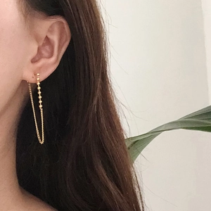 Detail of minimalist 18K gold plated titanium tassel chain earrings on a female model