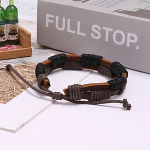 Close-up of brown and black braided leather bracelet with adjustable cord on vintage books