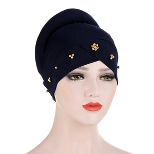 Navy blue turban cap with gold floral beading detail shown on a model head