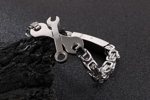 Détail du bracelet en acier titane argenté avec design créatif de clés croisées sur roche