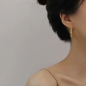 Elegant gold hoop earrings with beaded texture shown on a model for a stylish aesthetic