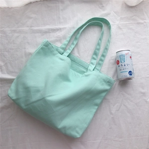Vue de dessus détaillée d'un sac cabas en toile vert menthe à plat sur un tissu blanc