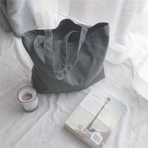 Détail d'un grand sac cabas en toile grise avec surpiqûres blanches de style minimaliste